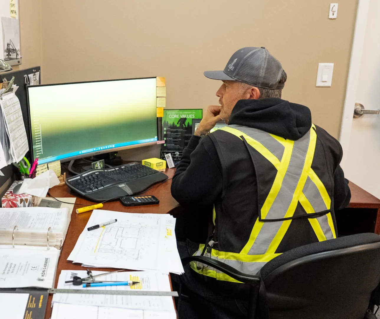 A crane operator works at his desk in front of a computer.