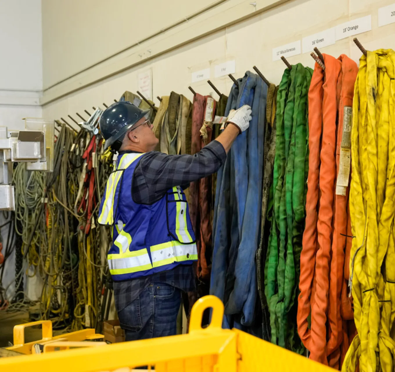 A worker selects rigging from a walll.