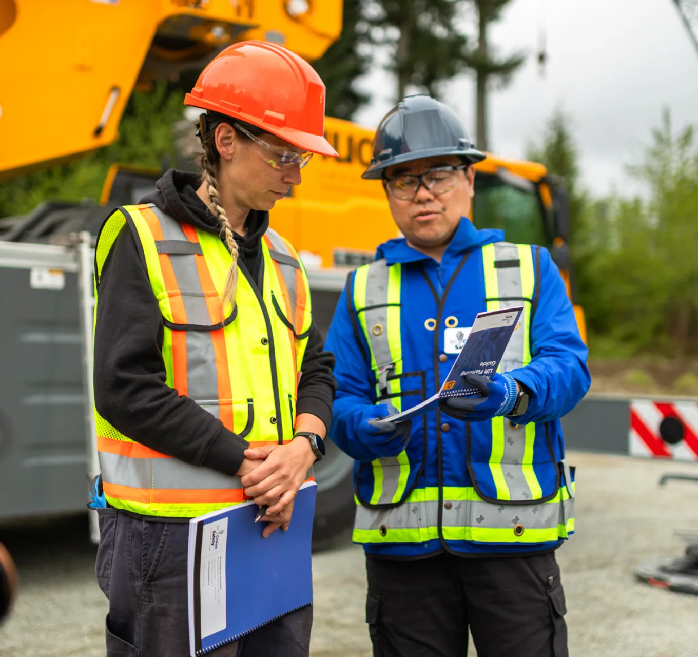 A female crane operator reviews resources with a supervisor.