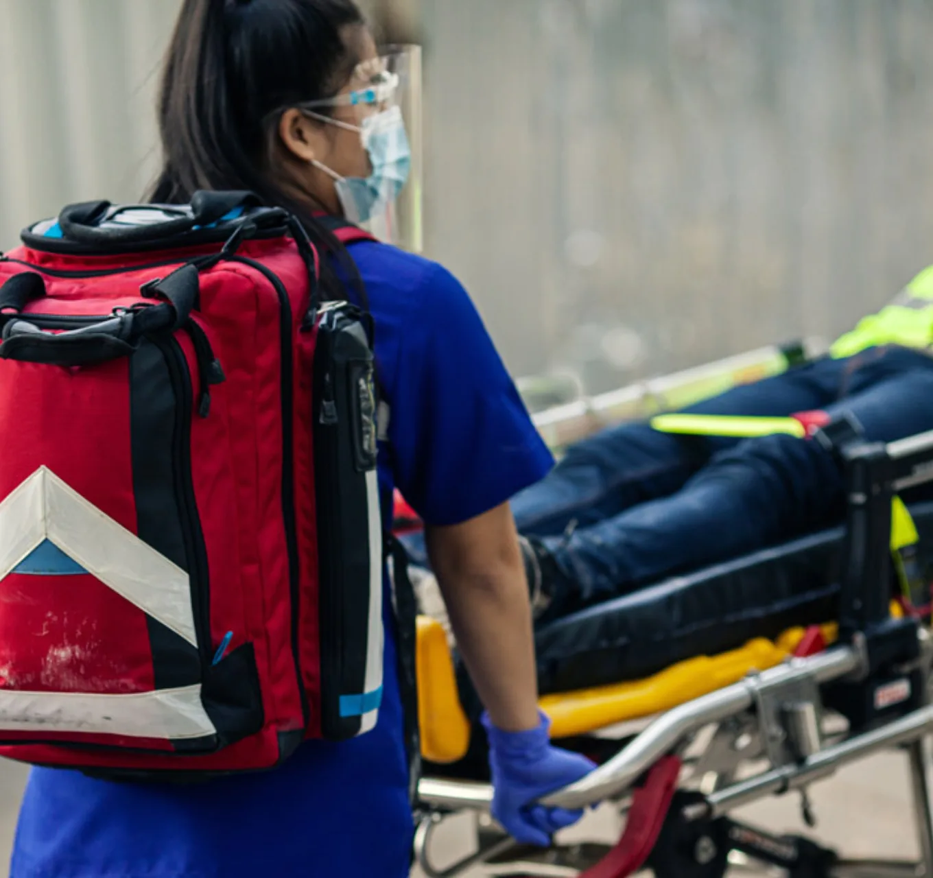 A paramedic rolls out a patient on a wheeled stretcher.