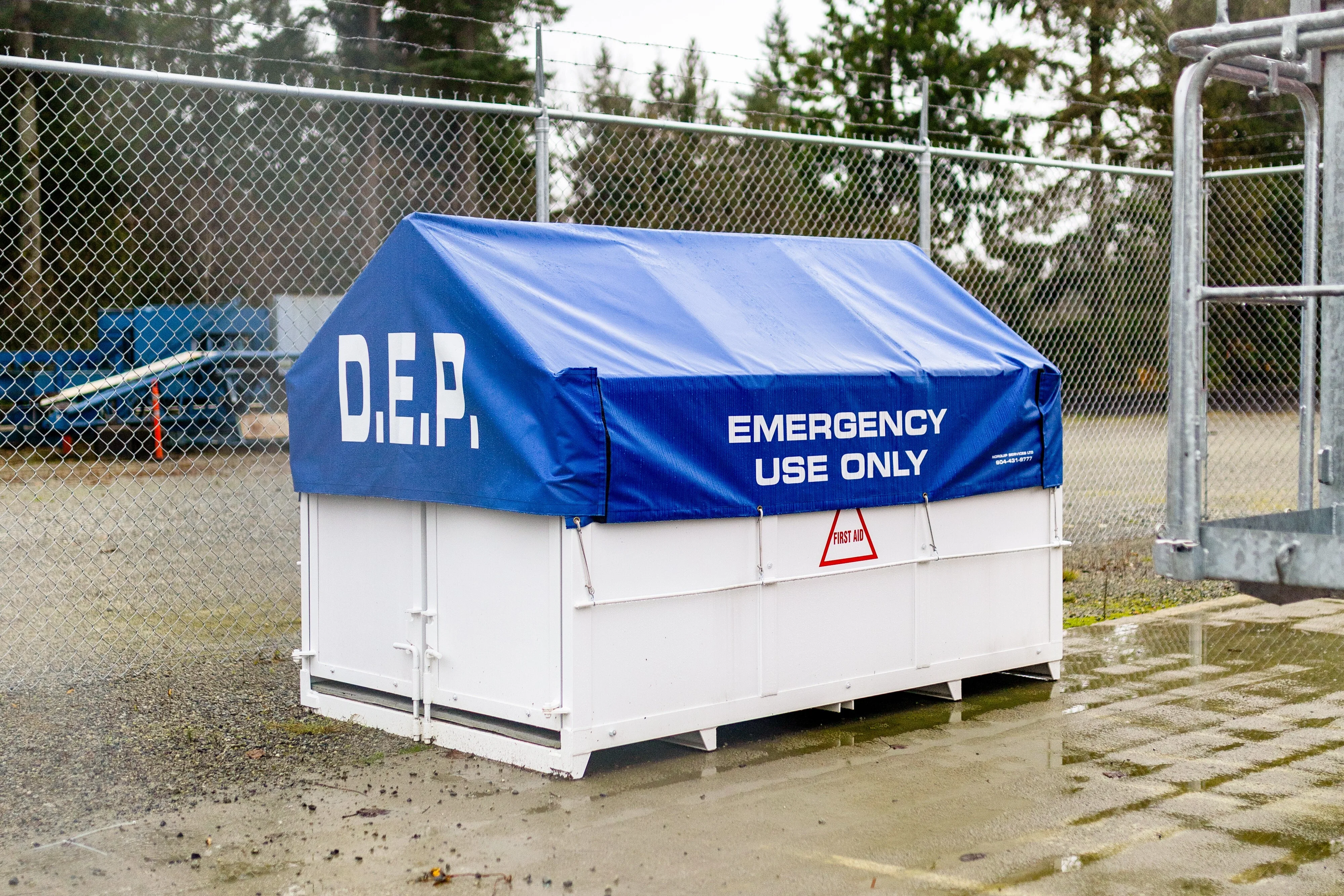 A white dedicated emergency platform (DEP) covered with a blue tarp on a worksite for emergency use only..