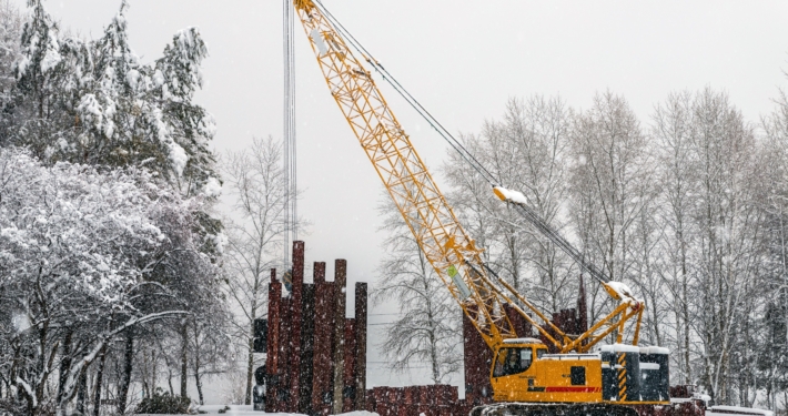 Mobile crane work in a park during snowfall. Work in bad weather conditions.