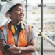 Woman who is black wearing a safety vest and hard hat working as a crane operator