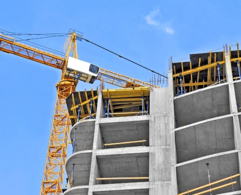 Crane and building construction site against blue sky
