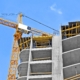 Crane and building construction site against blue sky